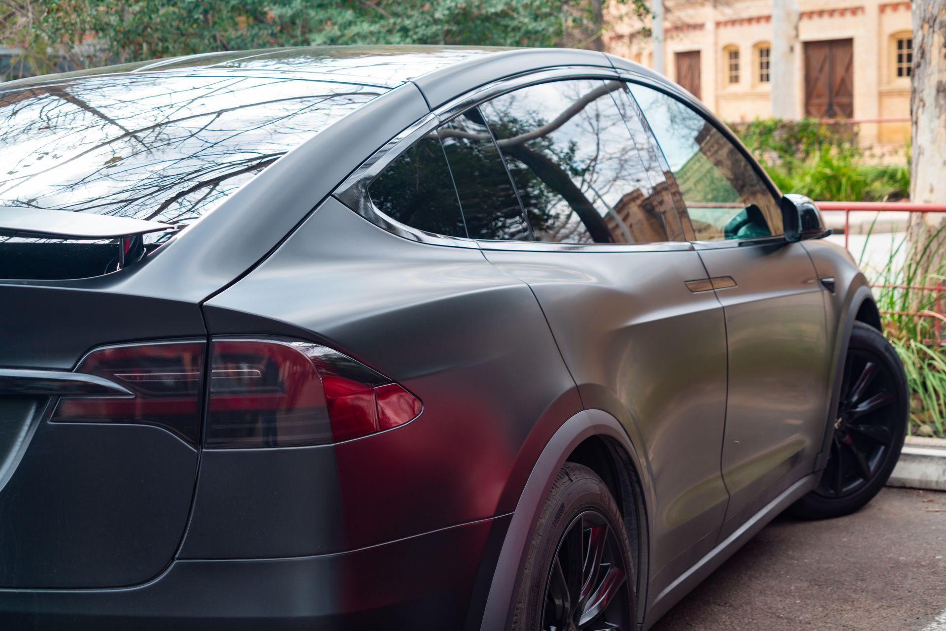 A matte black Tesla Model X parked outdoors, viewed from the rear three-quarter angle.